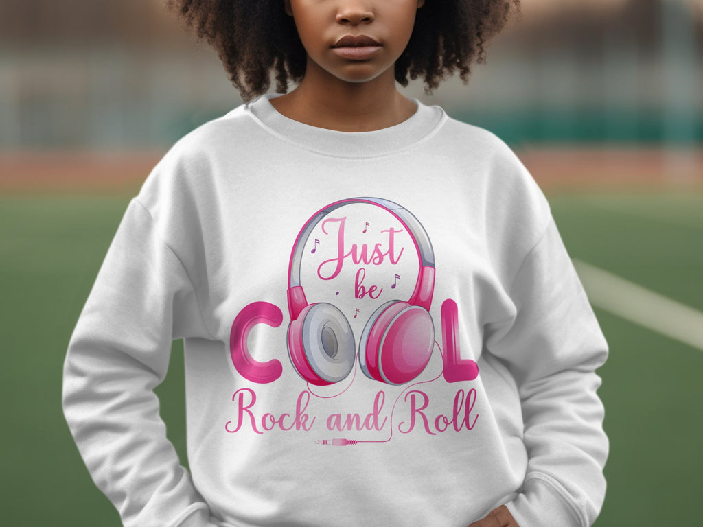 A fashion lover showcases a white Garment Graphics sweatshirt with pink and gray Rock and Roll headphones, featuring the text Just be cool Rock and Roll, ideal for music enthusiasts.