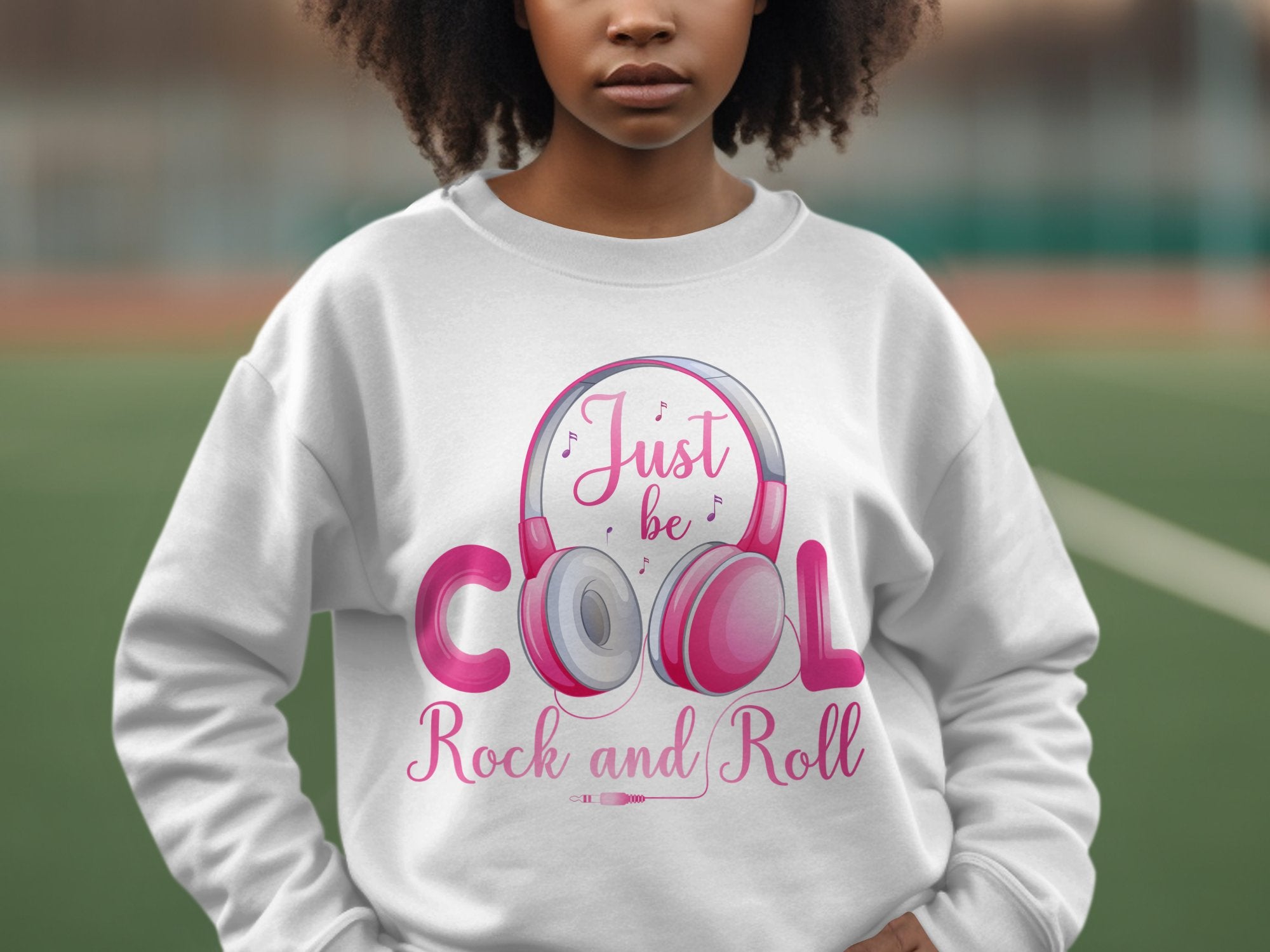 A fashion lover showcases a white Garment Graphics sweatshirt with pink and gray Rock and Roll headphones, featuring the text Just be cool Rock and Roll, ideal for music enthusiasts.