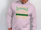 A person wearing a Garment Graphics light pink hoodie sports a green and yellow quote: If an Englishman gets run down by a truck he apologizes to the truck. The humorous text highlights English etiquette as the wearer looks downward.