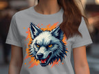 A person with long hair wears a Garment Graphics light gray T-shirt featuring a wolf print with a fierce expression. The design includes orange and red splatters, reflecting their bold personality, while the background appears blurred.