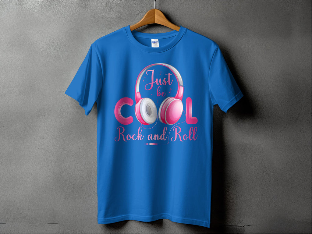 A blue Garment Graphics Rock and Roll T-shirt hangs on a wooden hanger against a gray backdrop, featuring fun headphones with pink and white text that says Just be Cool Rock and Roll, ideal for music enthusiasts.