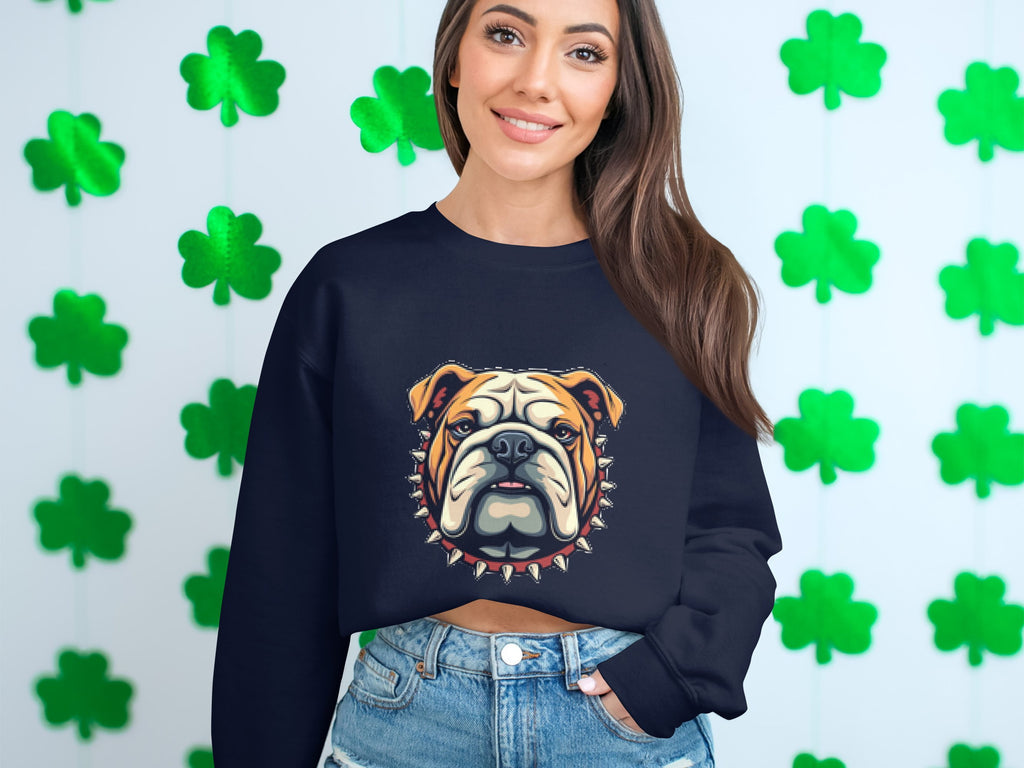 A person poses in front of a wall full of green shamrock cutouts, wearing denim shorts and a black Garment Graphics sweatshirt with a bulldog design.