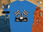 Flat lay showcasing Garment Graphics blue graphic T-shirt with race car and checkered flags, paired with jeans, sunglasses, headphones, keys, stylish watch, and an orange shirt on a wooden surface for a complete Formula One-inspired ensemble.