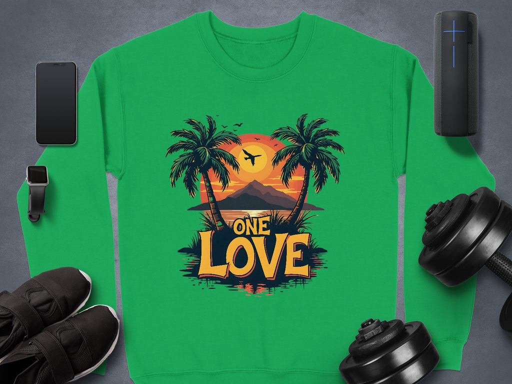 A green sweatshirt by Garment Graphics, featuring palm trees, a sunset, and One Love at the center, is displayed alongside a smartphone, smartwatch, speaker, dumbbells, and black sneakers.
