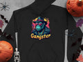 Garment Graphics presents a black hoodie exuding smokey cool style, featuring an anthropomorphic monkey in hat, sunglasses, chain, smoking above Gangster. It includes Halloween elements like pumpkins, bats, skeletons. Made from medium-heavy fabric for enhanced comfort and durability.