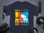 A Garment Graphics T-shirt featuring a DJ graphic and Dont Stop the Music slogan, ideal for music fans, lies on a gray background with a smartphone, smartwatch, shoes, portable speaker, and dumbbells. The design is vibrant with colorful elements.