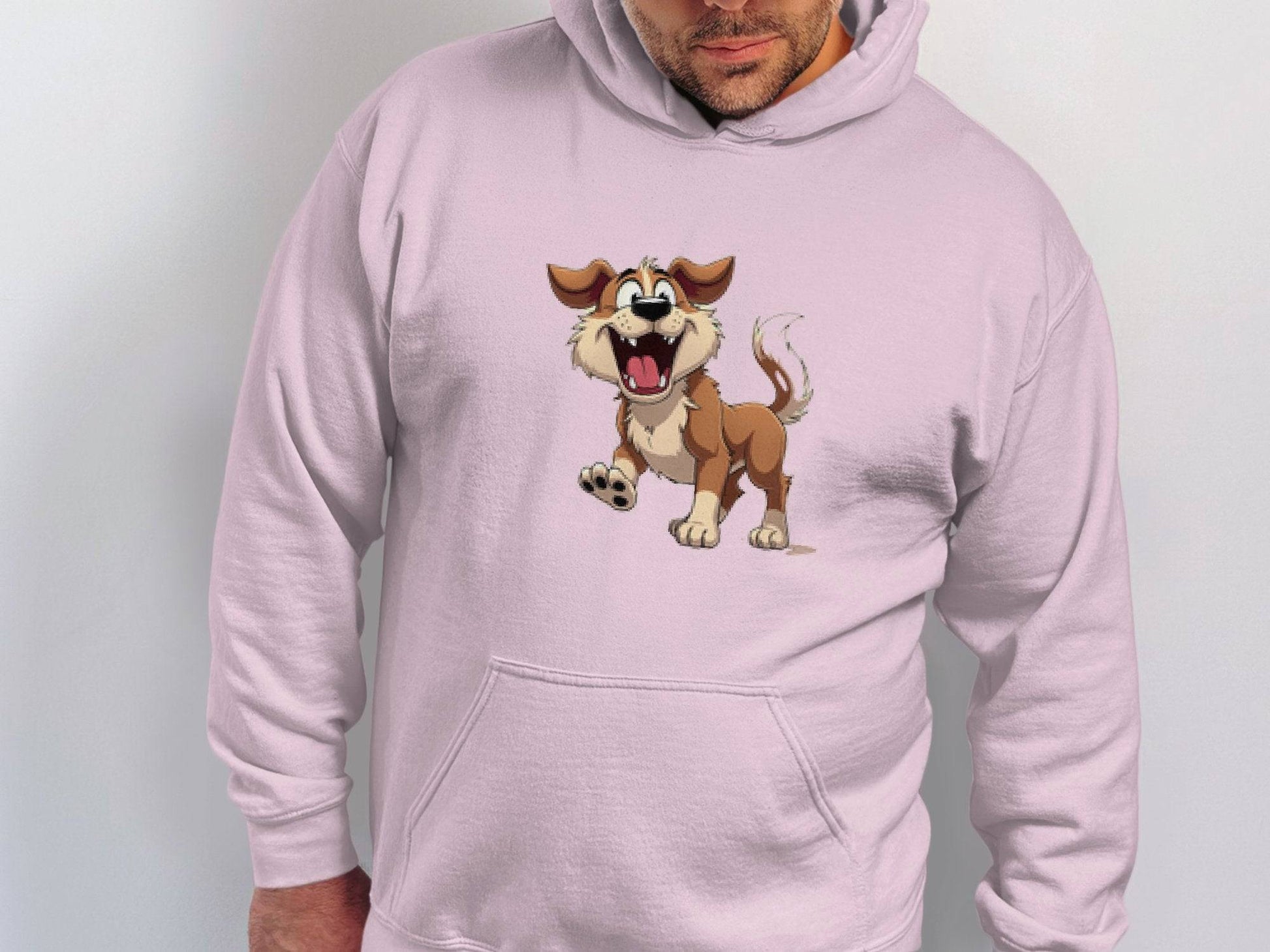 A person wears a light pink Garment Graphics hoodie featuring a cheerful animated brown and white cartoon puppy with an open mouth and wagging tail, perfect for dog lovers and capturing the lively spirit of canine companionship.