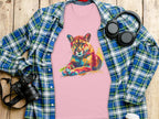 A Garment Graphics pink T-shirt with a colorful roaring cougar graphic is displayed on a wooden surface, surrounded by a blue and green plaid shirt, headphones, a camera, a coffee cup, and a smartphone.