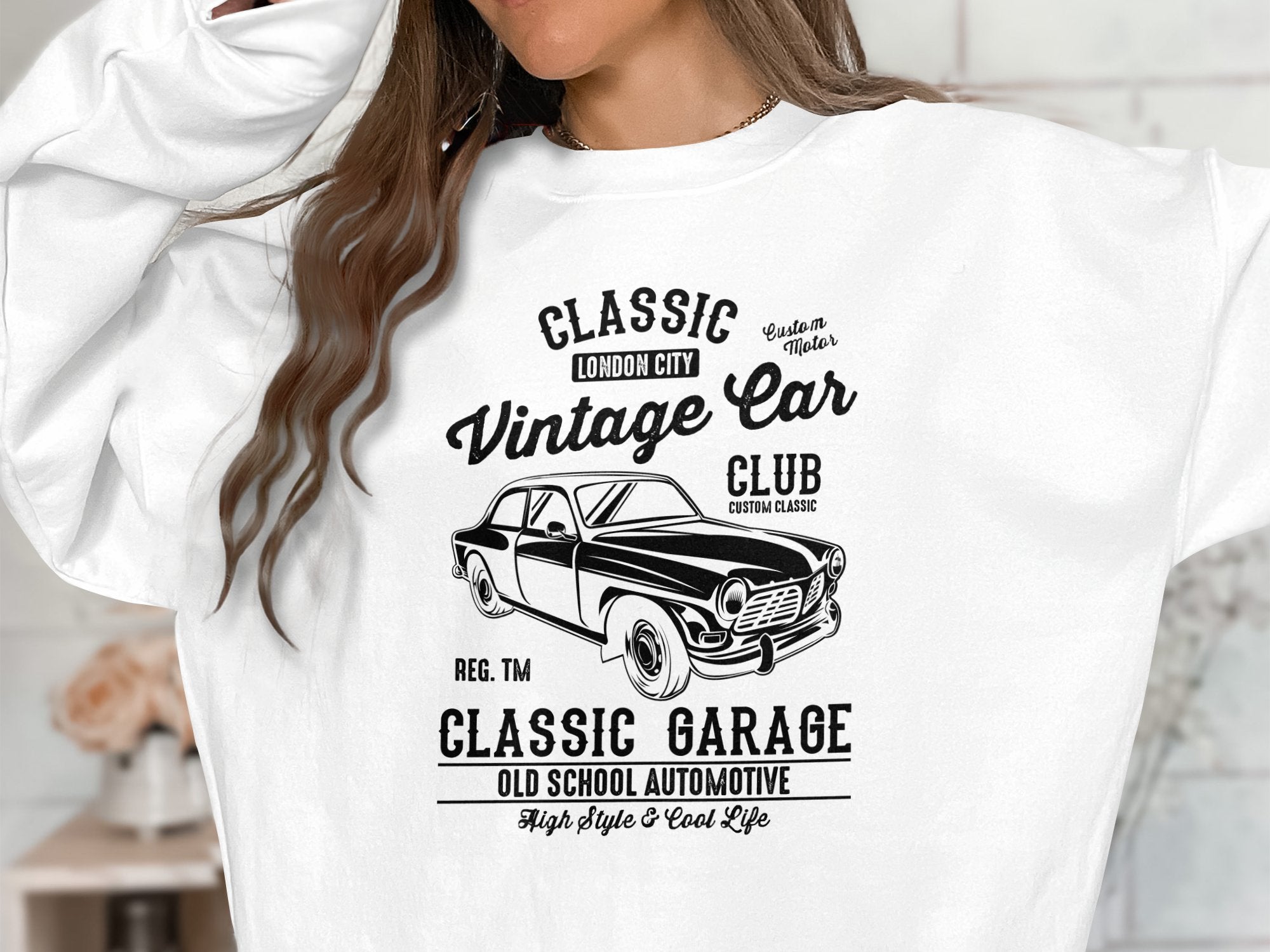 A person wears a Garment Graphics white sweatshirt featuring a vintage car design. It showcases Classic London City Vintage Car Club, Automotive Style, and declares Custom Classic and Classic Garage Old School Automotive for high style & a cool lifestyle.
