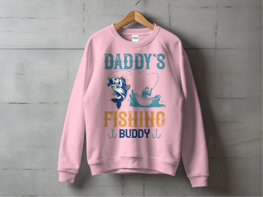 A person wearing Garment Graphics blue graphic sweatshirt features a fish, someone fishing in a boat, and Daddys Fishing Buddy in vibrant colors. Perfect for outdoor lovers, with snowy trees forming the blurred background.