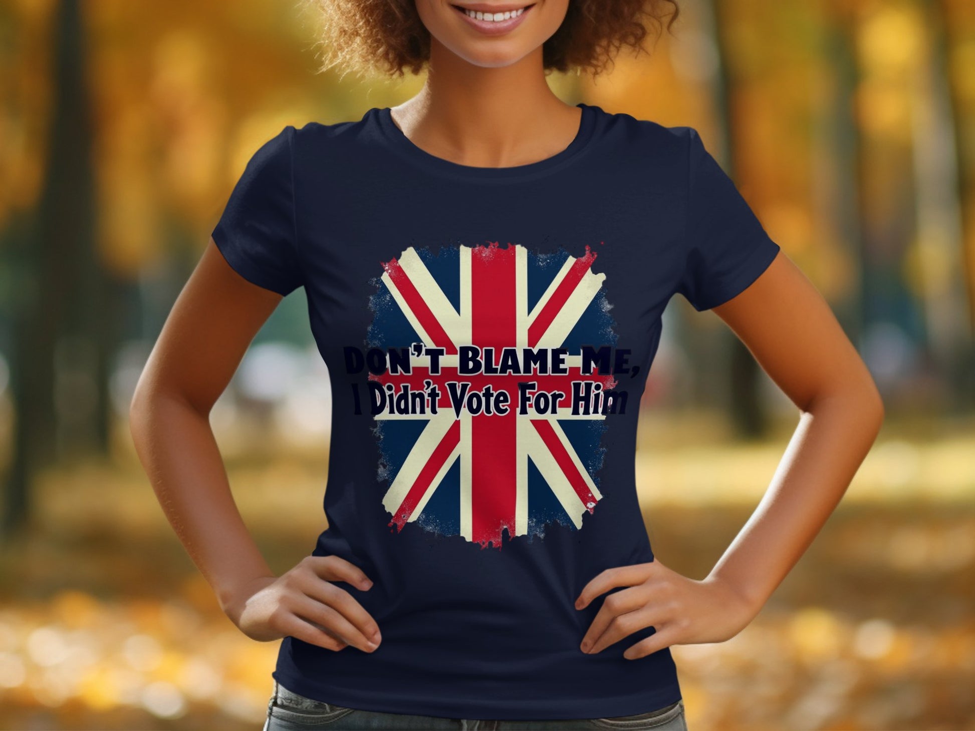 Garment Graphics presents a bold 100% cotton T-shirt, adorned with the Union Jack and the phrase Dont blame me, I didnt vote for him, set against a blurred autumnal outdoor scene, combining striking design with comfort and style.