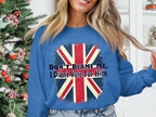 A person in a Garment Graphics blue sweatshirt with the Union Jack and Dont Blame Me, I Didnt Vote For Him stands by a Christmas tree with red and white decorations. This unisex sweatshirt ensures a comfortable fit.