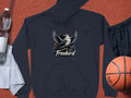 Laid on a surface with a basketball, black shorts, gray towel, and water bottle is a unique black Garment Graphics Freebird Graphic Pullover Hoodie featuring a bird with outstretched wings above the text Freebird.