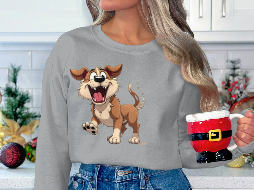 A person with long hair holds a Santa-themed mug, wearing a cozy gray Garment Graphics sweatshirt ideal for dog lovers. It features a playful animated happy dog illustration. Kitchen cabinets and vibrant holiday decorations create the festive backdrop.