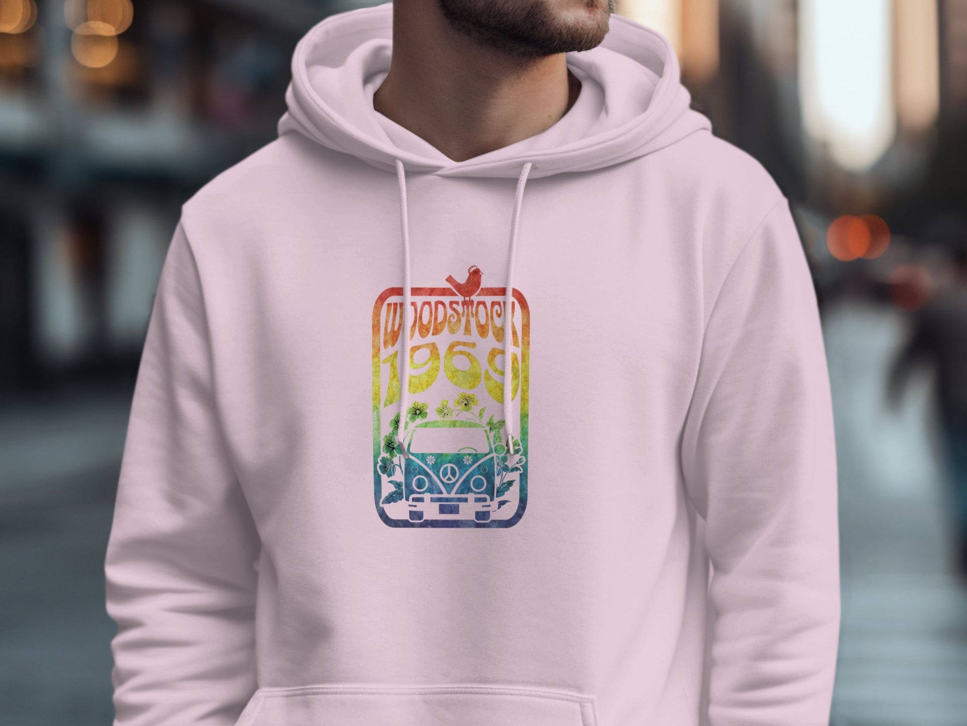 A person is wearing a Garment Graphics hoodie featuring a retro white graphic print that includes a vintage van, the word Woodstock, and the year 1969, all blending in a vibrant red-to-blue gradient.