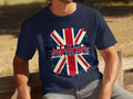 A person sits on a bench in a classic fit navy blue T-shirt by Garment Graphics, showcasing the Union Jack with the bold statement, Dont blame me, I didnt vote for him, above it. The individuals face is not visible in the image.