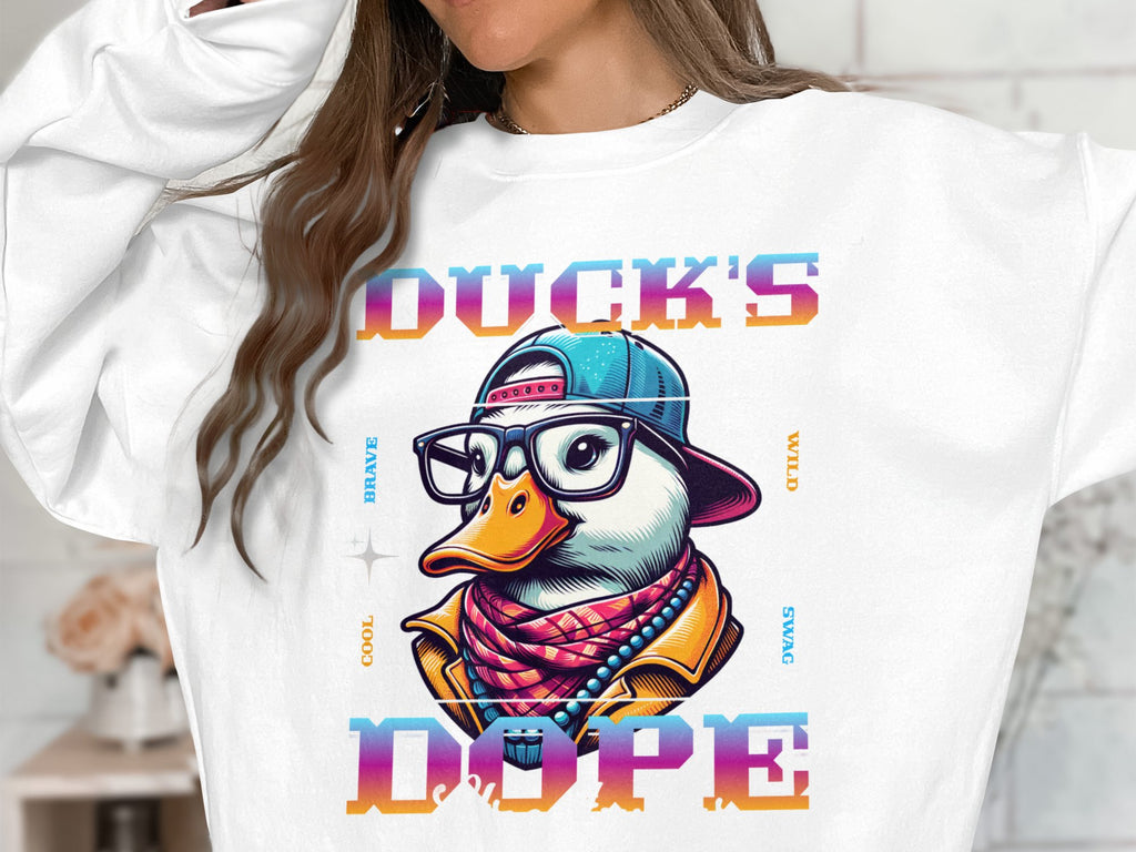 Someone is wearing a Garment Graphics white sweatshirt featuring a cartoon duck in glasses and colorful clothes. Ducks Dope is highlighted above and below the design, accompanied by words like Cool and Wild, creating a bold fashion statement.