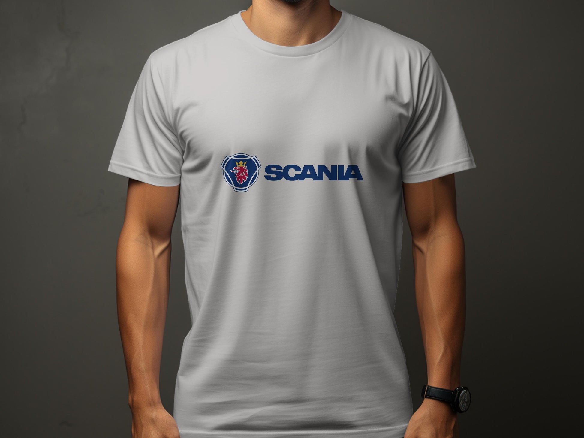 A person stands against a dark background wearing a white Garment Graphics cotton T-shirt displaying the Scania logo and emblem. With arms crossed, their upper body partially hides the sleek design of this popular Scania merchandise.