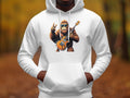 A person dons a white Garment Graphics hoodie featuring a cartoon gorilla playing guitar and showing a peace sign. Set against vibrant autumn colors, this Guitar Playing Gorilla Hoodie is perfect for animal lovers and music fans.