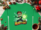 A green Garment Graphics sweatshirt features an Its Herotime graphic with a cartoon superhero. Surrounded by festive decorations like pine branches, ornaments, candy canes, and a hot beverage cup, this colorful design is perfect for adventure-loving youth during the holidays!.
