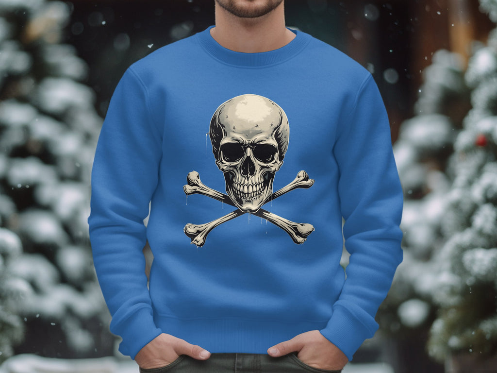 Wearing Garment Graphics blue skull and crossbones graphic print sweatshirt, a person stands amidst snow-covered trees, their edgy style contrasting the serene winter landscape.