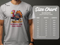 A person dons a light gray Garment Graphics T-shirt with a vibrant cartoon turkey and Turkey on the Run text. Beside them is a size chart for the classic fit Gildan 5000 shirt, detailing sizes S to 5XL with corresponding width and length measurements in inches.