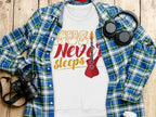 A flat lay photo features Garment Graphics plaid shirt, a vibrant Music Never Sleeps guitar-themed sweatshirt, over-ear headphones, a camera, and a coffee cup lid on wood—a perfect setup for music lovers.
