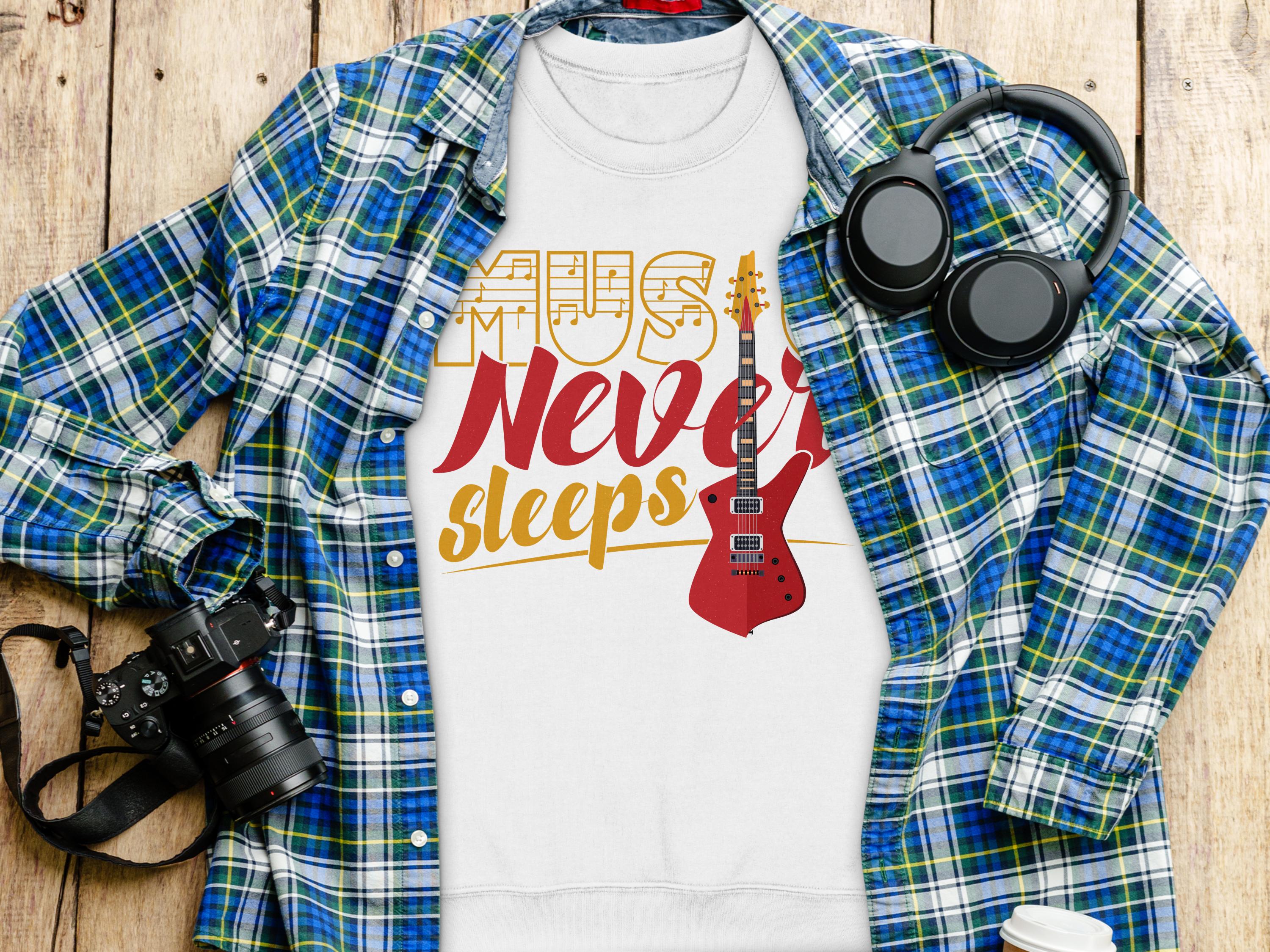 A flat lay photo features Garment Graphics plaid shirt, a vibrant Music Never Sleeps guitar-themed sweatshirt, over-ear headphones, a camera, and a coffee cup lid on wood—a perfect setup for music lovers.