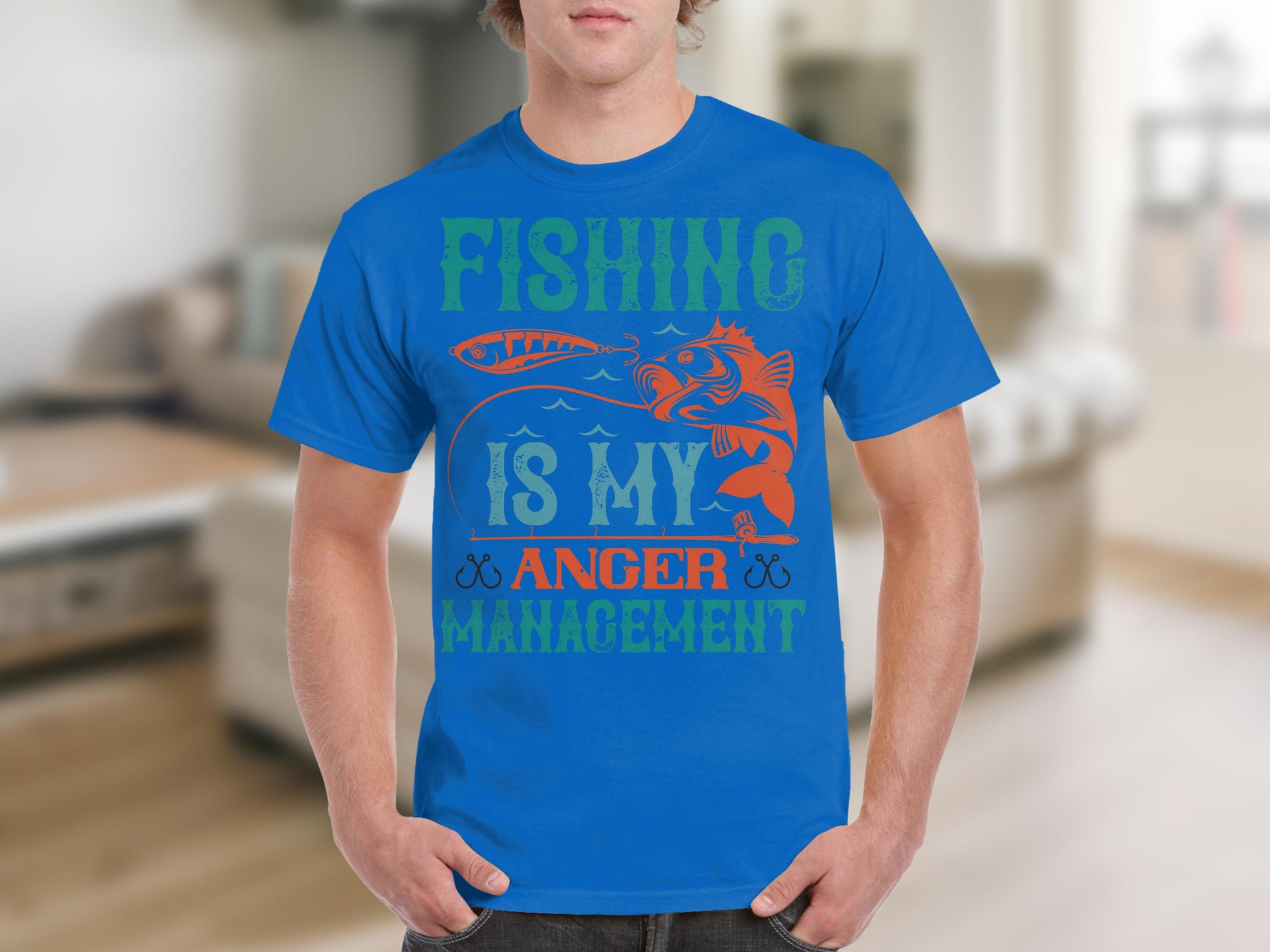 A fishing enthusiast wears a Garment Graphics blue T-shirt with Fishing Is My Anger Management adorned with a fish and lure. The subtly blurred indoor backdrop highlights the shirts bold design, embodying relaxation and passion for fishing.