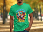 Wearing a bright green Garment Graphics T-shirt adorned with a colorful dog in sunglasses, the shirt reads Paw-sitive Stylish and Chillin Like A Canine Villain, matching the serene vibe of the autumn trees in the background.