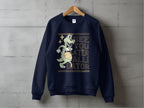 Garment Graphics navy blue unisex sweatshirt showcases a cartoon alligator with a beach ball and the caption, See you later alligator on the front. Displayed against a concrete wall backdrop.