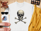 On a wooden surface, a white Garment Graphics sweatshirt with a skull and crossbones design sets an edgy scene, accented by makeup brushes, sunglasses, a makeup palette, a yellow jacket, pink shoes, nail polish, and a small blue pouch.