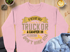A pink sweatshirt from Garment Graphics with the slogan If hes got golf clubs in his truck or a camper in his driveway, I dont hire him sits on a table. Next to it, a denim shirt complements an outdoor vibe with latte art coffee and scattered pebbles.