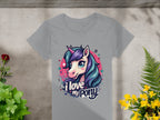 Gray Garment Graphics t-shirt featuring a cartoon unicorn with colorful hair and stars, plus the text I love my pony. Set on concrete with plants and flowers, its a dream for unicorn enthusiasts and fans of I Love My Pony T-Shirts.