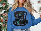 A person in a Garment Graphics blue sweatshirt with a top hat design and St Patricks Day text, accented by two small shamrocks. A decorated Christmas tree enhances the festive mood.