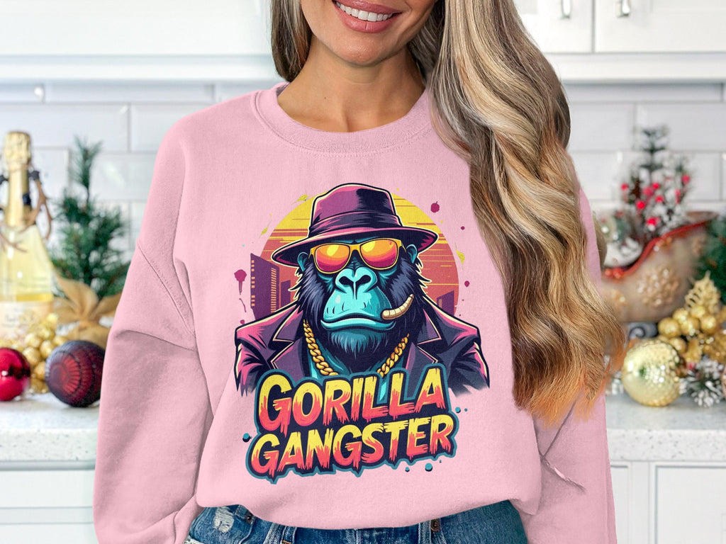 In an urban-style kitchen with holiday decor, a woman sports a pink Garment Graphics sweatshirt showing a gorilla in a suit, sunglasses, and hat. The bold text Gorilla Gangster under the image seamlessly merges fashion with flair.