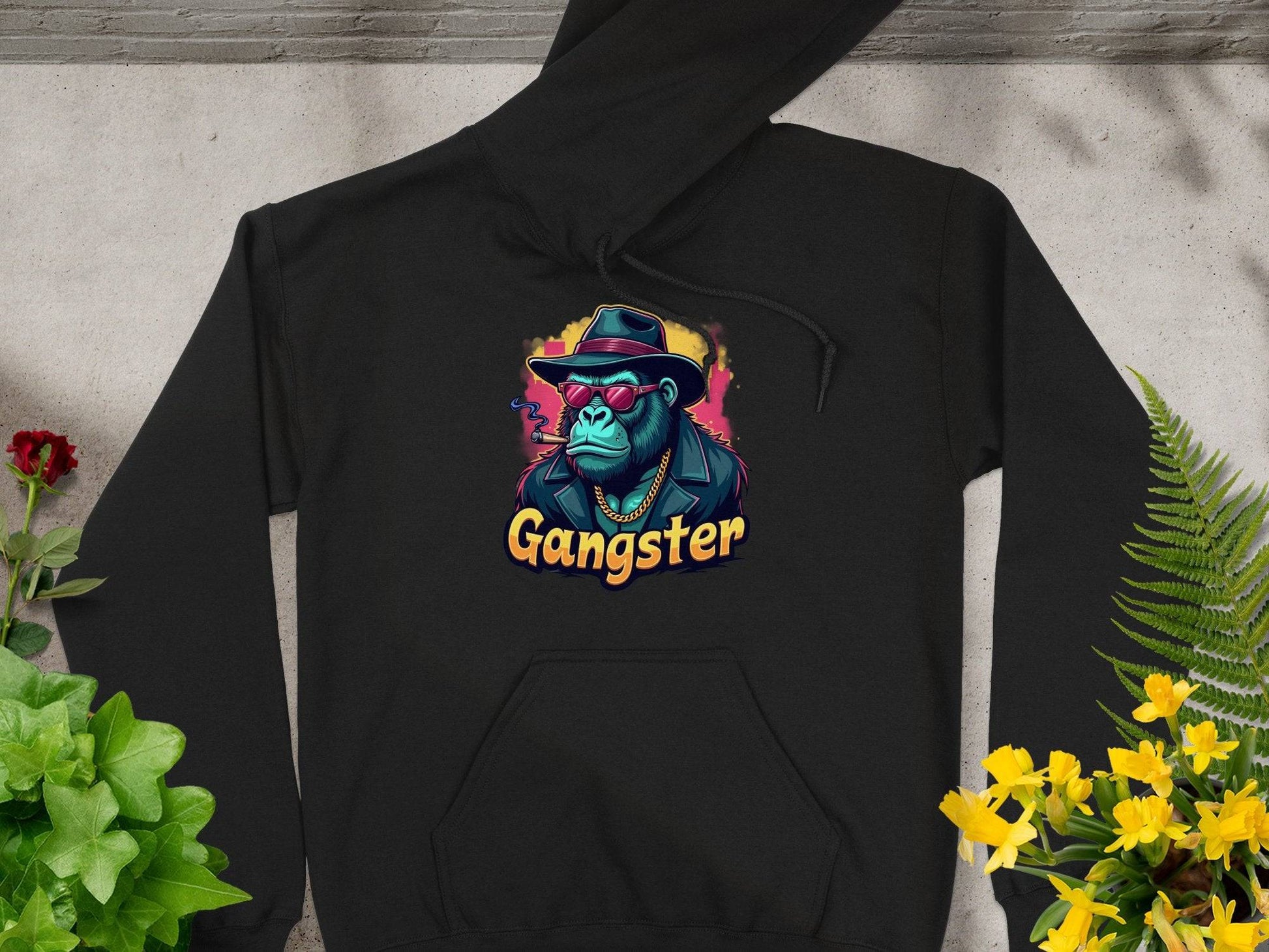 Garment Graphics presents this black hoodie featuring a smokey cool style in medium-heavy fabric. The centerpiece is a gangster gorilla graphic with a hat, sunglasses, and chain, Gangster below, artfully surrounded by vibrant green plants and small red flowers for an edgy vibe.