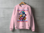 A pink Garment Graphics sweatshirt hangs against a concrete wall, displaying a cartoon duck with a baseball cap, glasses, and scarf. DUCKS DOPE is in bold colors on this unisex, medium-heavy fabric sweatshirt for ultimate comfort and cool swag.