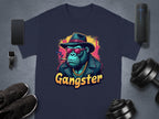 The Gangster Gorilla T-Shirt by Garment Graphics showcases a navy blue design with a gorilla in a fedora, sunglasses, leather jacket, and cigar. Gangster is boldly printed below. This urban classic fit pairs well with accessories like phones, smartwatches, shoes, dumbbells, etc.