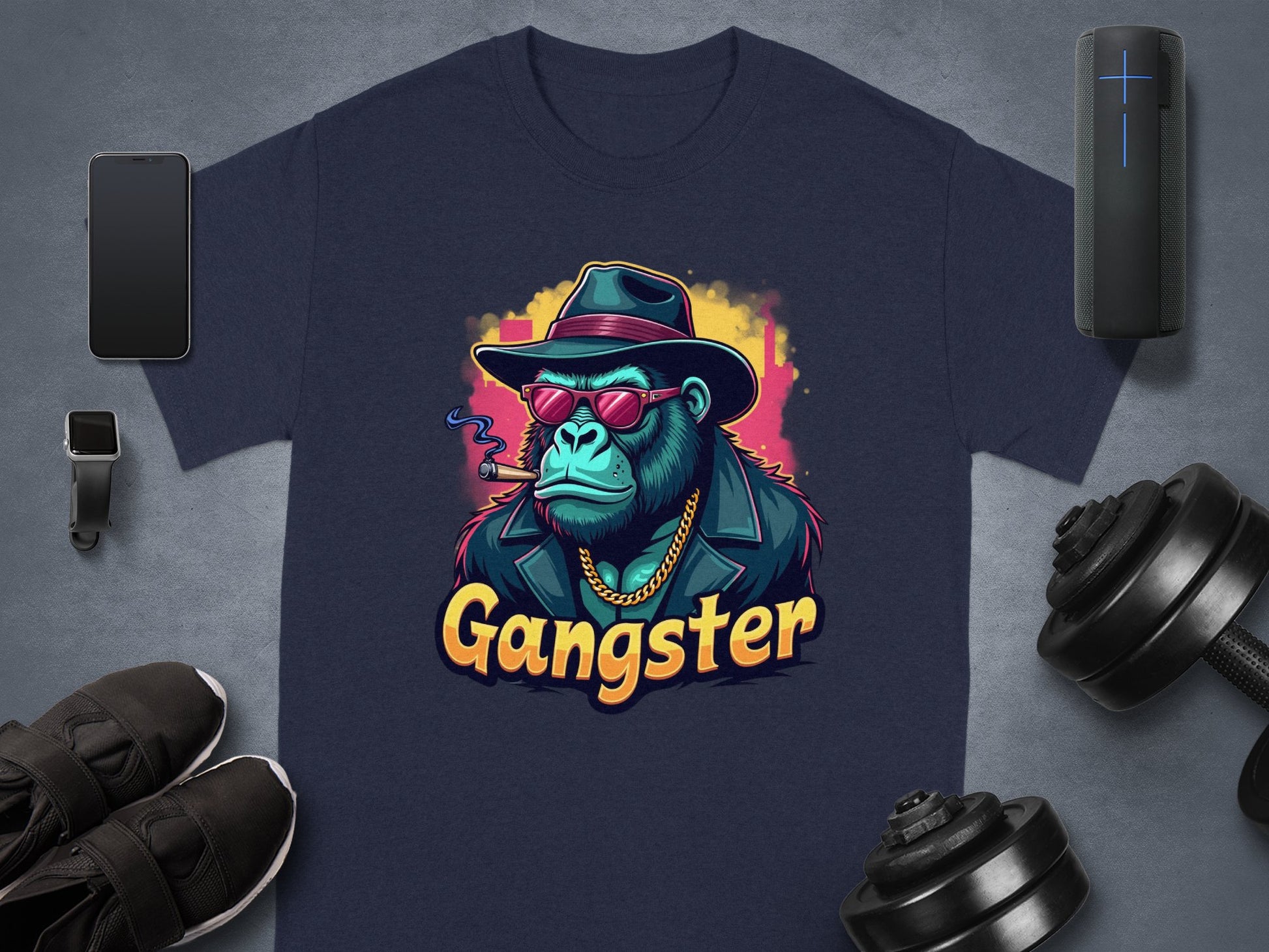 The Gangster Gorilla T-Shirt by Garment Graphics showcases a navy blue design with a gorilla in a fedora, sunglasses, leather jacket, and cigar. Gangster is boldly printed below. This urban classic fit pairs well with accessories like phones, smartwatches, shoes, dumbbells, etc.