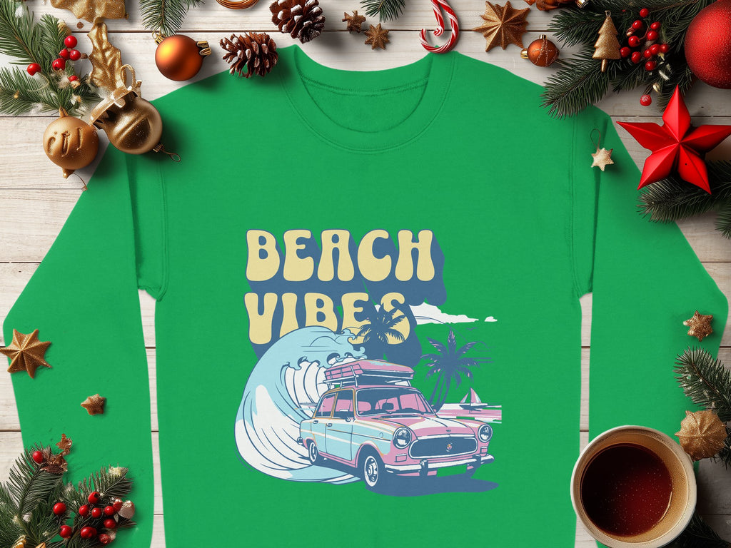 The Garment Graphics green shirt has a retro roadtrip graphic featuring a vintage car, surfboard, wave, and palm trees with Beach Vibes text. Showcased with Christmas decor on wood, it includes ornaments, pine cones, and coffee. Available in unisex sizing for comfort.
