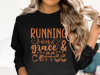A person with long, wavy hair wears a Garment Graphics unisex graphic sweatshirt that says Running on Grace & Coffee in bold orange letters with playful coffee cup icons, embodying casual elegance.