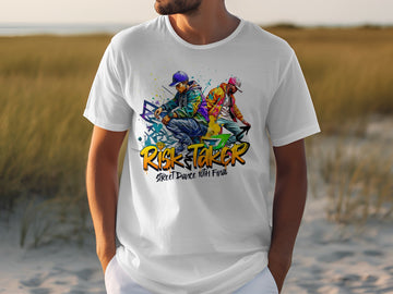 A man wears a Garment Graphics white t-shirt with vibrant graffiti-style art of two dancers and Risk Taker Street Dance 10th Final. He stands outdoors, embodying street dance culture against a backdrop of grass and sand with a blurred horizon.
