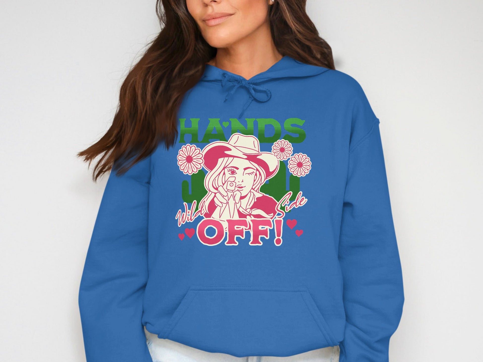 Dressed in a vibrant blue hoodie by Garment Graphics, one displays a graphic of a pointing figure amidst flowers, with HANDS OFF! in bold green and pink. This long-sleeve statement piece effortlessly captures attention.