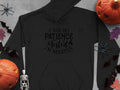 The Garment Graphics black hoodie says, I had my patience tested. Im negative, and is surrounded by Halloween decor—pumpkins, bats, a skeleton, and spiders on gray—a perfect choice for fans of unique, humorous statement hoodies.