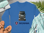 Garment Graphics blue graphic crewneck sweatshirt features a Scania truck and logo. Surrounding it are plants, sandals, a watch, a striped shirt, and a small handbag on gray—the perfect piece for truck enthusiasts.