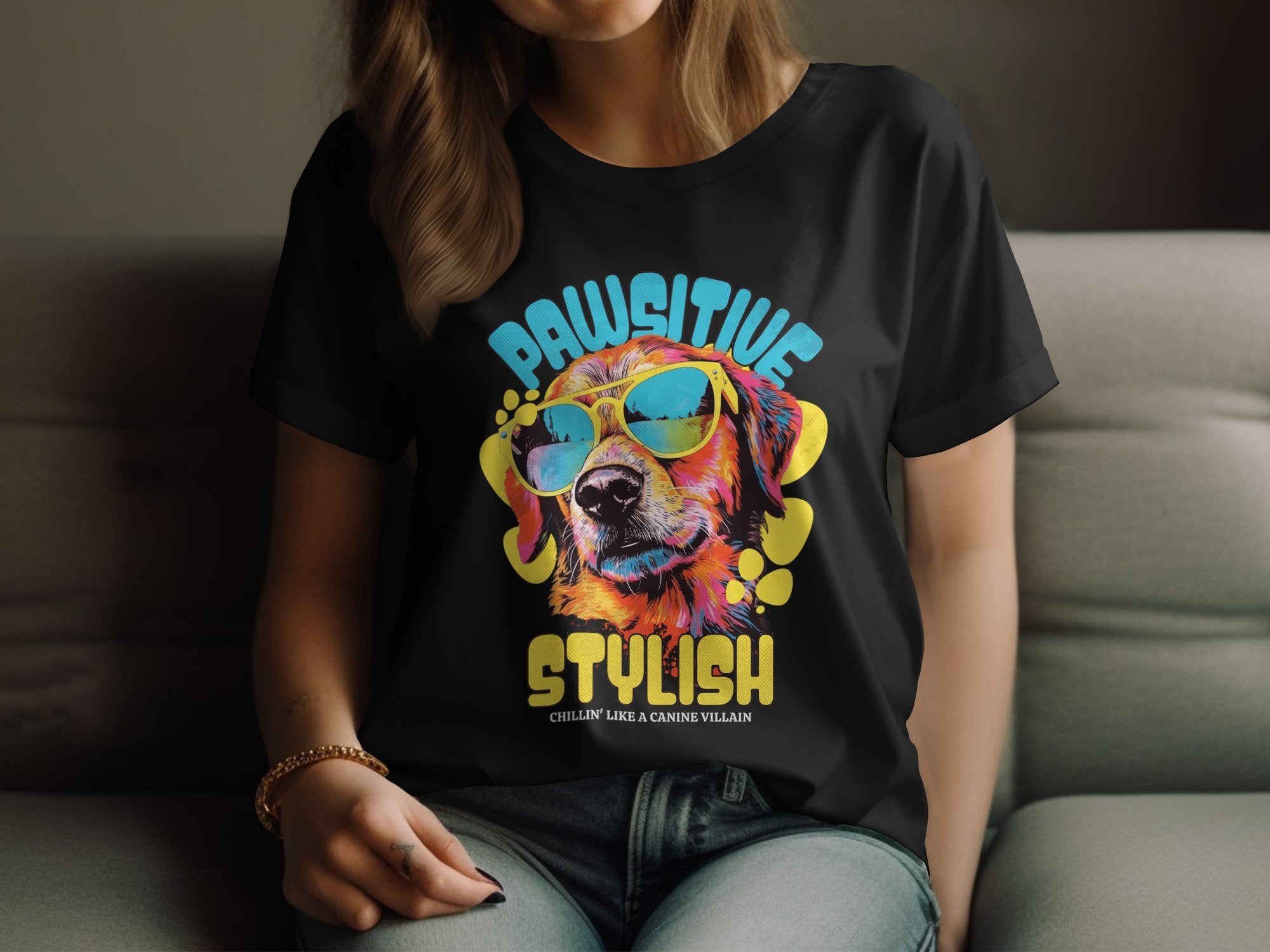 A person wears a black Dog T-Shirt by Garment Graphics, featuring a colorful dog with sunglasses. The text reads, Pawsitive Stylish Chillax like a canine villain. This relaxed and stylish design is tailored for womens sizing with part of their face visible.
