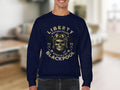 A person wearing a navy Garment Graphics sweatshirt with a skull in a vintage pilot helmet graphic, biker-style. Text says Liberty Motorcycle Specialist Blackpool 2023 with two crossed wrenches, against a softly focused room backdrop.