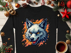 A Garment Graphics black shirt with a fierce wolf graphic on an orange splatter background is displayed. It’s surrounded by Christmas decorations, pinecones, star anise, and a coffee cup on wood, making a bold statement with your wild side.