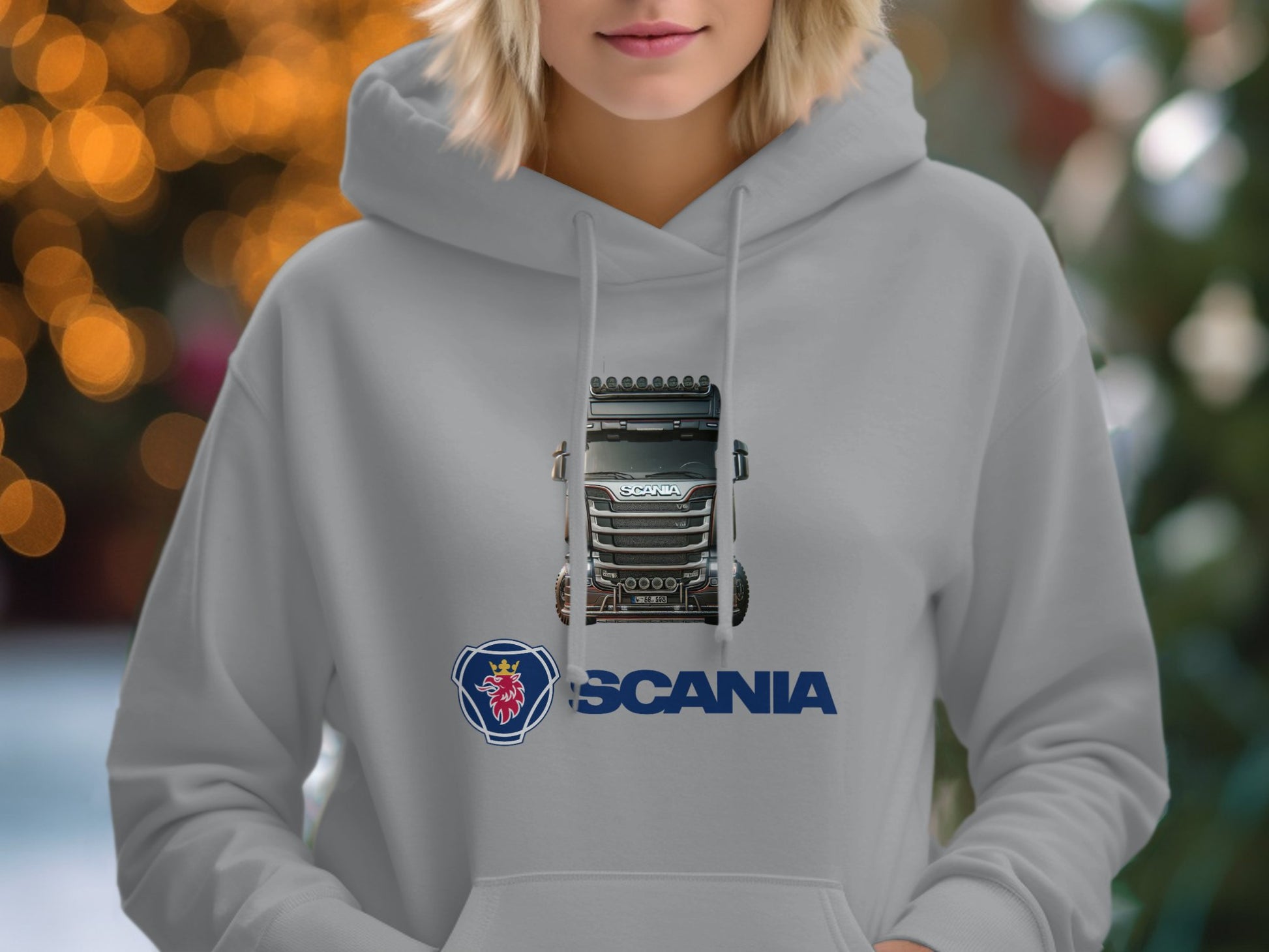 A gray Garment Graphics Scania Truck Hoodie displays a truck and iconic logo, set against a softly blurred backdrop of warm lights, ideal for truck enthusiasts who love graphic prints.